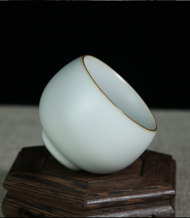 The picture of the tea bowl with moon-white glaze of Ru Kiln. The tea bowl has a simple and elegant shape, with an open mouth, a curved belly and a small circular foot. The lines are smooth and natural. The moon-white glaze evenly covers the inner and outer walls of the bowl. The glaze surface is smooth and delicate, like fat or jade, giving people a warm, smooth and mellow texture. 