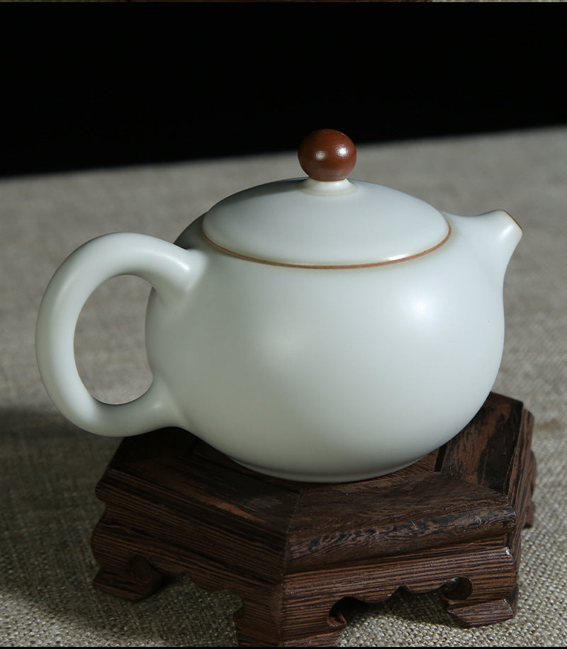 The picture of the teapot with moon-white glaze of Ru Kiln. The body of the teapot has smooth and elegant lines, being round and full, showing a simple, unsophisticated and magnificent modeling style. Its moon-white glaze is like the first snow in winter, with a slight bluish-gray tint in the whiteness, emitting a soft luster under the light, giving people a sense of coolness and elegance. The spout and the handle of the teapot are exquisitely designed with a harmonious proportion, perfectly integrating wit