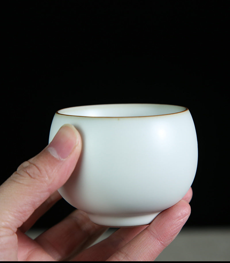 The picture of the tea bowl with moon-white glaze of Ru Kiln. The tea bowl has a simple and elegant shape, with an open mouth, a curved belly and a small circular foot. The lines are smooth and natural. The moon-white glaze evenly covers the inner and outer walls of the bowl. The glaze surface is smooth and delicate, like fat or jade, giving people a warm, smooth and mellow texture. 