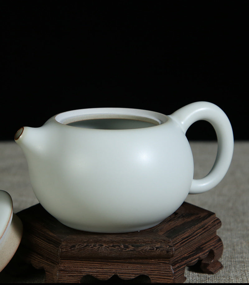 The picture of the teapot with moon-white glaze of Ru Kiln. The body of the teapot has smooth and elegant lines, being round and full, showing a simple, unsophisticated and magnificent modeling style. Its moon-white glaze is like the first snow in winter, with a slight bluish-gray tint in the whiteness, emitting a soft luster under the light, giving people a sense of coolness and elegance. The spout and the handle of the teapot are exquisitely designed with a harmonious proportion, perfectly integrating wit