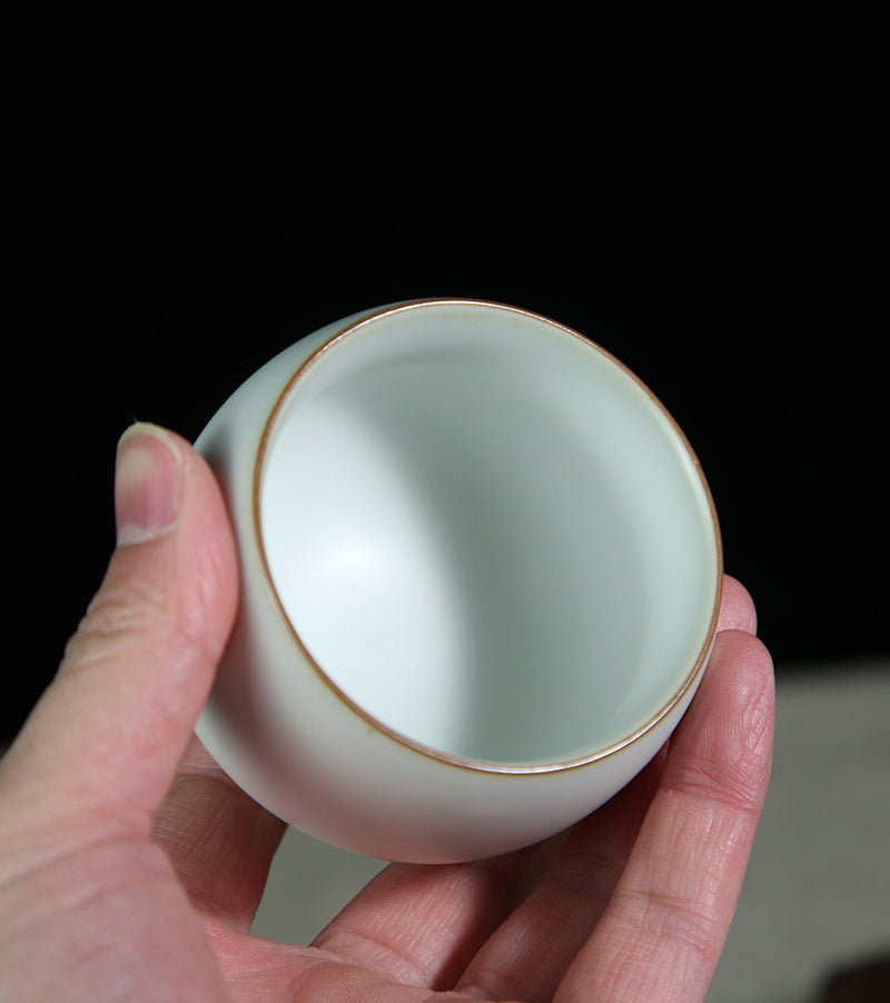 The picture of the tea bowl with moon-white glaze of Ru Kiln. The tea bowl has a simple and elegant shape, with an open mouth, a curved belly and a small circular foot. The lines are smooth and natural. The moon-white glaze evenly covers the inner and outer walls of the bowl. The glaze surface is smooth and delicate, like fat or jade, giving people a warm, smooth and mellow texture. 