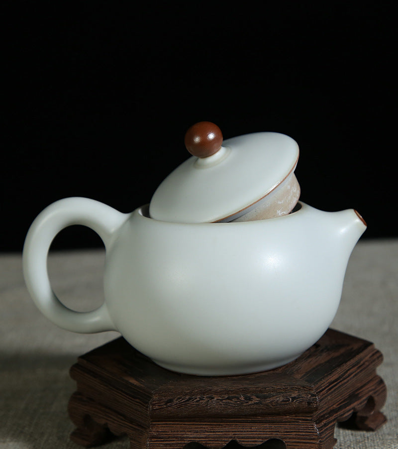 The picture of the teapot with moon-white glaze of Ru Kiln. The body of the teapot has smooth and elegant lines, being round and full, showing a simple, unsophisticated and magnificent modeling style. Its moon-white glaze is like the first snow in winter, with a slight bluish-gray tint in the whiteness, emitting a soft luster under the light, giving people a sense of coolness and elegance. The spout and the handle of the teapot are exquisitely designed with a harmonious proportion, perfectly integrating wit